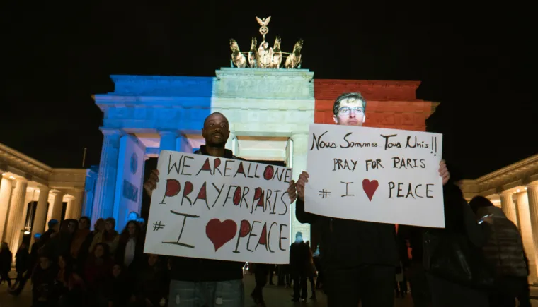 Svijet suosjeća s Parizom: simboli gradova u bojama  francuske zastave, cvijeće i svijeće za žrtve