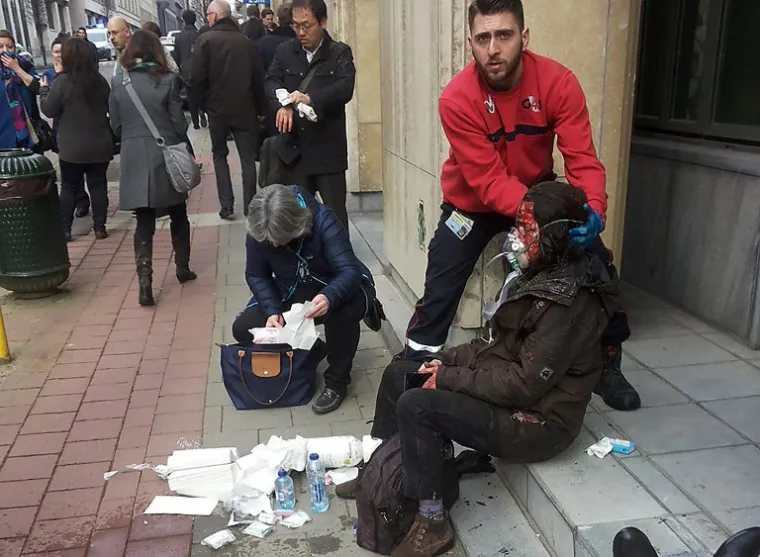 Pripadnik privatnog osiguranja pomaže ranjenoj ženi ispred Maalbeek postaje.