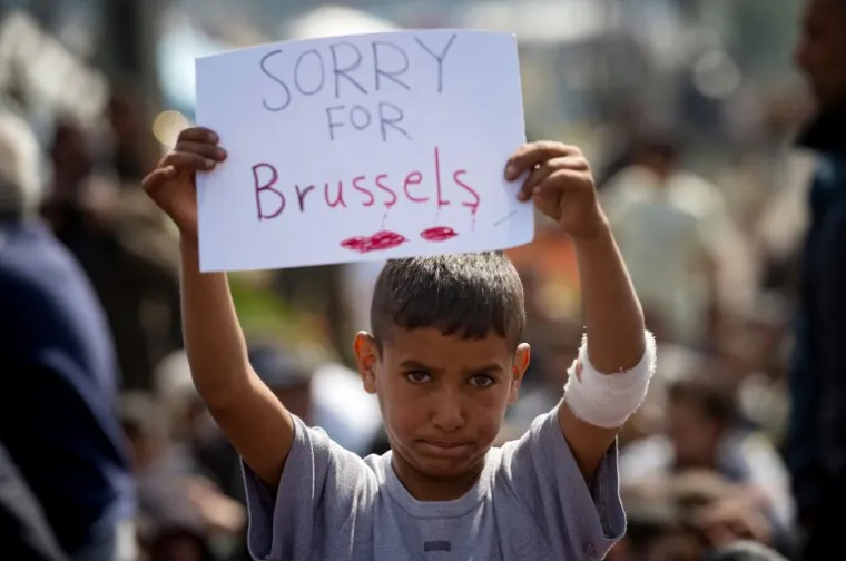 Dječak drži natpis kojim izražava suosjećanje sa žrtvama terorističkih napada u Bruxellesu tijekom protesta u improviziranom logoru kod sela Idomeni na grčko-makedonskoj granici. Grčka neće biti u stanju na vrijeme početi slati izbjeglice natrag u Tursku, izjavila je grčka vlada, dok se ta zemlja trudi sprovesti ključni dogovor čiji je cilj olakšavanje europske izbjegličke krize.
