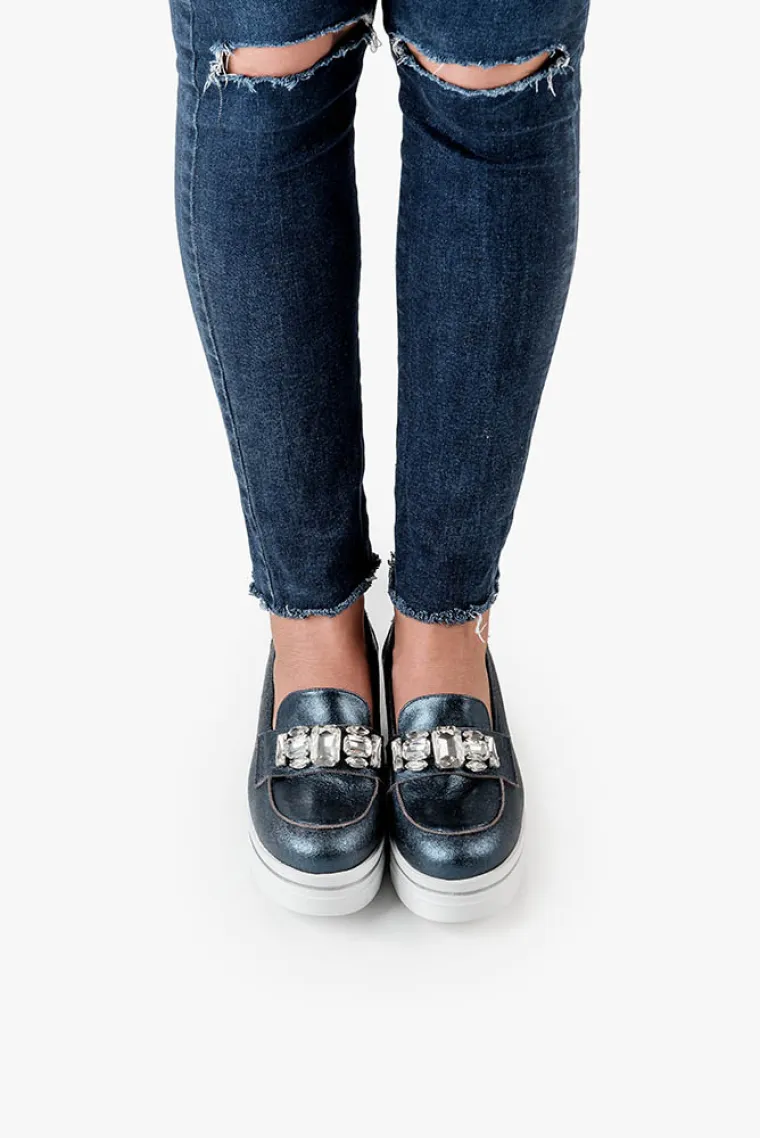 Za proljetnu sezonu Guliver predlaže statement modele u zlatnim, srebrnim, brončanim i indigo metalik nijansama. Vladavina flatformi nastavlja se i dalje, ali s laganim stilskim zaokretom u obliku neobičnih key detalja poput apliciranih zvjezdica i sjajnih chunky kristala koji bude asocijacije na dekadentne sedamdesete i eru glam rocka.