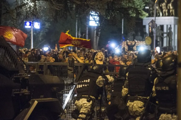 Žena maše makedonskom zastavom pred policijom koja pokušava blokirati ulaz prosvjednicima u makedonski parlament.