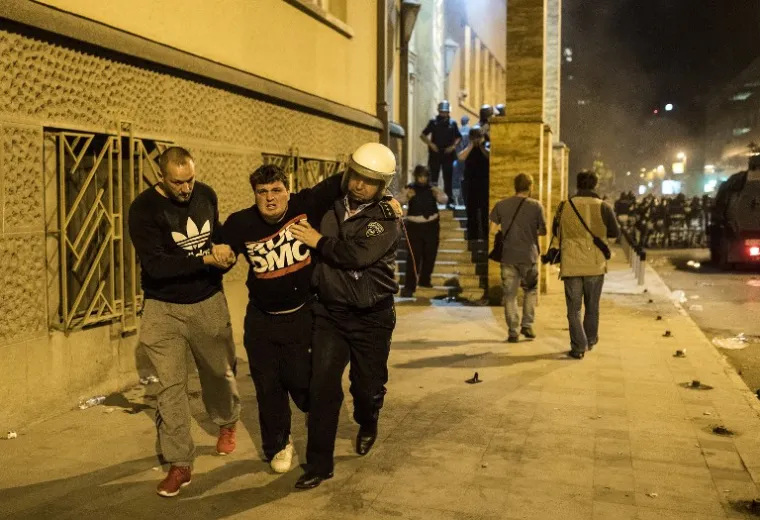 Policajac nosi ozljeđenog čovjeka nakon sukoba prosvjednika i policije.