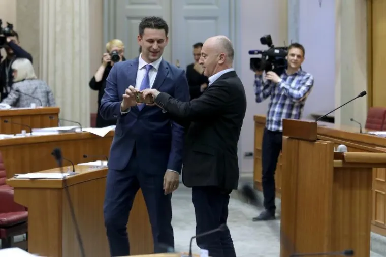 Božo Petrov i Predrag Matić razmjenjuju mobitele kako bi se fotografirali u sabornici.