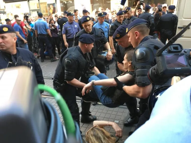 20-ak aktivista i aktivistkinja je zapriječilo prolaz sudionicima i sudionicama Hoda za život. Policija se približila i odnosi jednog po jednog aktivista i aktivistkinju, koji su mirno sjeli pred kolonu i ne odupiru se ni dok ih policija odnosi u maricu.