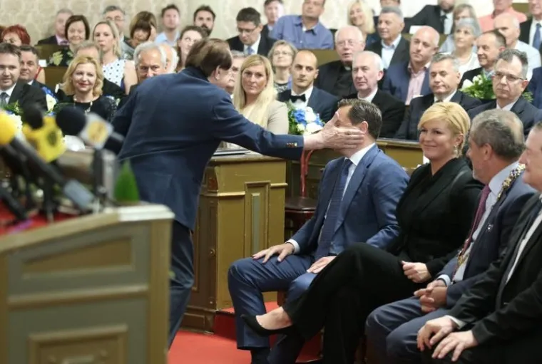 Na svečanoj sjednici povodom Dana grada na kojoj je gradonačelnik Zagreba Milan Bandić uručio povelje i nagrade Grada Zagreba, akademik Josip Božičević je nakon svog govora "simpatičnom pljuskom" pozdravio Predsjednika gradskog HDZ-a Andriju Mikulića, &scaron;to je izazvalo različite reakcije okupljenih. Predsjednica Republike Kolinda Grabar-Kitarović u to je vrijeme čistila mrlju na hlačama...