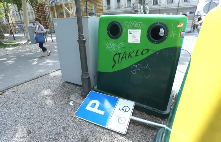 Pored spremnika za otpad nalazi se odbačeni znak parkinga za bicikle