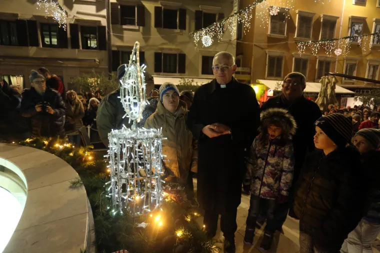 Rijeka - Prvu svijeću na adventskom vijencu postavljenom oko fontane na Koblerovom trgu upalio je riječki nadbiskup msgr Ivan Devčić u društvu gradonačelnika Vojka Obersnela i učenika Centra za odgoj koji su ukrasili adventski vijenac.