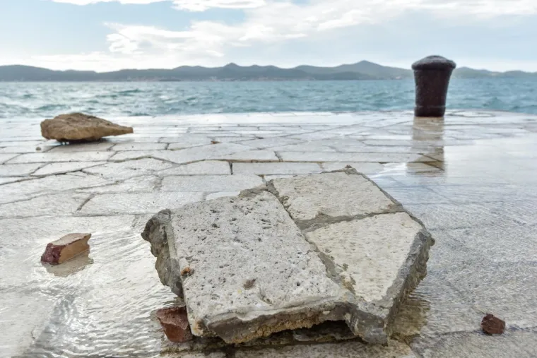 Inače prekrasna zadarska riva sinoć je razornim djelovanjem valova viskih i 4 metra te&scaron;ko o&scaron;tećena. Mul je gotovo u potpunosti potpuno uni&scaron;ten, a od prethodnih juga podlokana riva na mjestima je razrovana poput razbacanih kockica koje opet treba složiti na svoje mjesto. O&scaron;tećenja se vide i kod instalacije Morske orgulje a prve procjene govore da se radi o milijunskim &scaron;tetama.