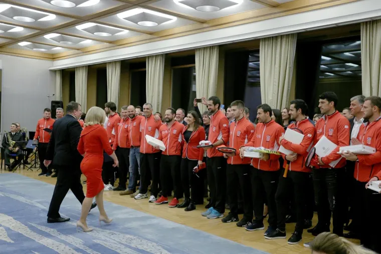 Predsjednica Kolinda Grabar-Kitarović odlikovala je pobjednike Davis Cupa. Za tu prigodu odjenula je vatreno crvenu usku haljinu do koljena koju su krasili zlatni detalji te kopče na ramenu.  Uz nju je  iskombinirala i cipele u boji kože.