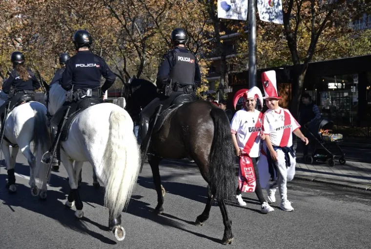 Fans of River Plate smile as mounted police officers pass by in the surroundings of the Santiago Bernabeu stadium in Madrid, hours before the start of the second leg match of the all-Argentine Copa Libertadores final between River Plate and Boca Juniors on December 9, 2018. (Photo by Javier SORIANO / AFP)