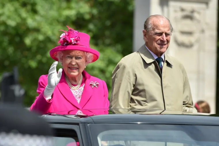 Britain's Queen Elizabeth II (L) and Britain's Prince Philip (R), Duke of Edinburgh wave to guests from their car as they attend the Patron's Lunch on the Mall, an event to mark her official 90th birthday in London on June 12, 2016.   / AFP PHOTO / POOL / BRUCE ADAMS
