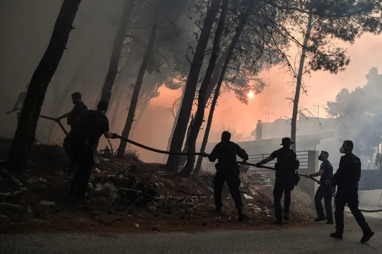 Policijski službenici pomažu vatrogascima u gašenju požara u Thrakomakedonesu, u blizini planine Parnitha, sjeverno od Atene, 7. kolovoza 2021. godine.