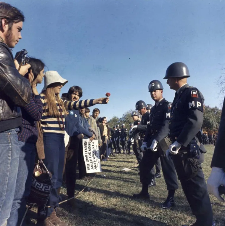 11. &apos;Marš na Pentagon&apos;, Albert R. Simpson (1967.): Demonstranti su prosvjedovali zbog rata u Vijetnamu tijekom svih godina u kojem se vodio s masovnim demonstracijama koje su se redovito održavale diljem zemlje i u glavnom gradu. Ova fotografija je snimljena tijekom slavnog &quot;Marša na Pentagon&quot;, 21. listopada 1967. Na njoj je sudjelovalo 100.000 demonstranata u Washingtonu, DC, a 35.000 ih je marširalo prema Pentagonu.

Snimio ju je stožerni narednik tijekom prosvjeda ispred Pentagona u Arlingtonu, VA. Albert R. Simpson iz Army Signal Corps, a prikazuje antiratnog prosvjednika koji vojnom policajcu nudi cvijet u znak mira.

