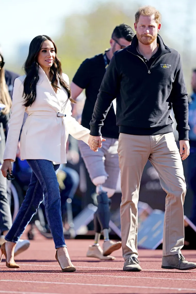 Meghan Markle je na Igrama nosila ležernu modnu kombinaciju kao i princ Harry. Vojvotkinja je nosila dugi, bijeli sako s remenom, obične traperice mrkva kroja te smeđe štikle od brušene kože. Dok se princ Harry pojavio u bež hlačama, plavom puloveru i sivim cipelama.