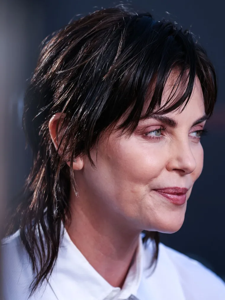 Nova frizura Charlize Theron je slojevita, uz pixie rez sa strane i stilizirana u njezin uobičajeni kosi bob. Također je nosila svježe ošišane tanke šiške.
