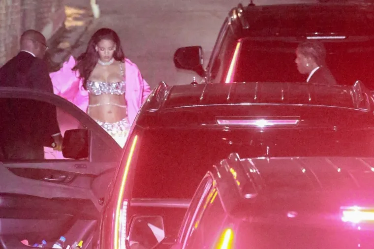 Rihanna je na zabavi nosila srebrnu metalik kombinaciju - šljokičasti top i hlače. Outfit je uskladila ružičastim kaputom, kao i debelom dijamantnom ogrlicom i naušnicama. 