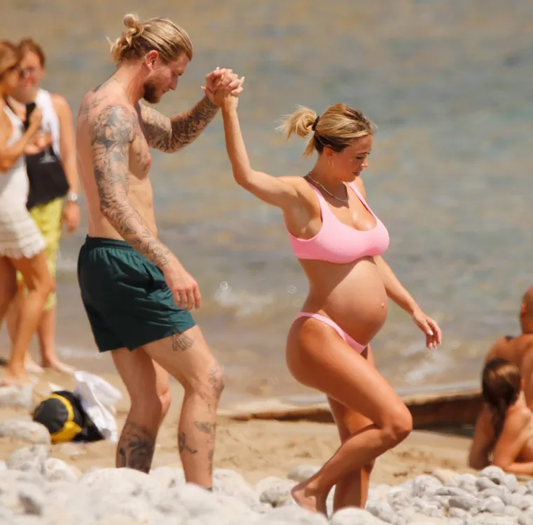 Atraktivna voditeljica privlači poglede i upija zrake sunca na plaži, a njezin dragi uz nju zijeva