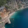 Plaža je kombinacija pijeska i šljunka, a more je bistro i tirkizno plavo.