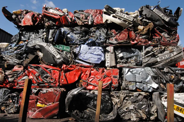 Zgnječeni automobili stoje u ogromnoj hrpi na dvorištu za reciklažu i otkup automobila.