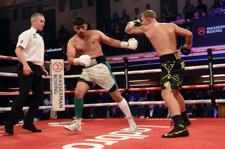 Hasnan Ali je 22-godi&scaron;njak je bio na listi boksača u York Hallu, ali nije imao potvrđenog protivnika do 24 sata prije borbe. Većina je očekivala da će Ali lako pobijediti boksača koji je uletio na shorte notice, ali Sams je imao drugačije planove. Ali nije uspio doći k sebi od kanonade udaraca i sudac je ubrzo prekinuo borbu kada je Sams počeo dominirati. Nakon borbe, Ali je sjedio u kutu ringa i zbrinuli su ga liječnici. Ni&scaron;ta mu nije bilo jasno. Izgledao je lo&scaron;e, bio dezorijentiran. 