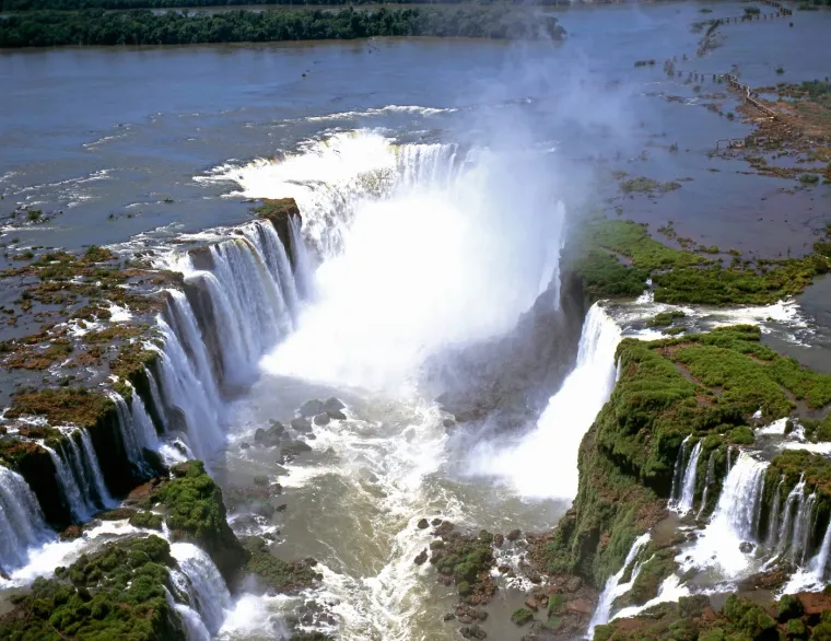 9. Slapovi Iguazu, Argentina/Brazil: Slapovi Iguazu nalaze se između Brazila i Argentine i može im se pristupiti iz obje zemlje. Rijeka Igua&ccedil;u teče kroz Brazil većim dijelom, ali većina slapova nalazi se na argentinskoj strani. Slapovi nastaju na &scaron;irokom prostranstvu gdje se rijeka Igua&ccedil;u slijeva preko ruba visoravni Paran&aacute; uz zaglu&scaron;ujući huk. Oko 275 pojedinačnih kaskada oblikuje gotovo 3 kilometra dug lanac vodopada. Sama veličina ovog čuda prirode će vas zapanjiti. Đavolje grlo, stijena u obliku slova U s 14 vodopada koji se spu&scaron;taju s visine od 80 metara, najveličanstveniji je dio ovog čuda prirode.