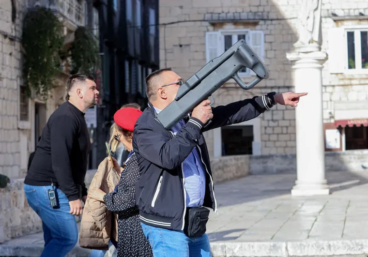 Na jednoj fotografiji vidi se kako je čovjek uperio prema nebu zanimljivu spravu. U potpisu stoji kako zaštitari skidaju dron. 