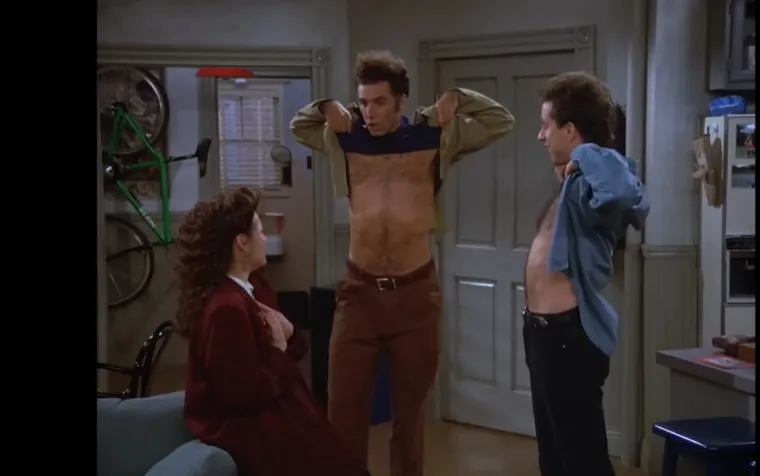 Elaine zamoli Kramera da je fotografira za božićnu čestitku, ali ne shvaća da joj je gumb na ko&scaron;ulji otkopčan. Tek nakon &scaron;to je poslala čestitke obitelji, prijateljima i kolegama, Elaine primijeti nezgodu i postane poznata kao "Bradavica" u uredu. George, koji nije dobio čestitku, ljutito se požali, na &scaron;to Elaine vikne: "Hoće&scaron; božićnu čestitku?" i gurne mu lice u svoje grudi. 