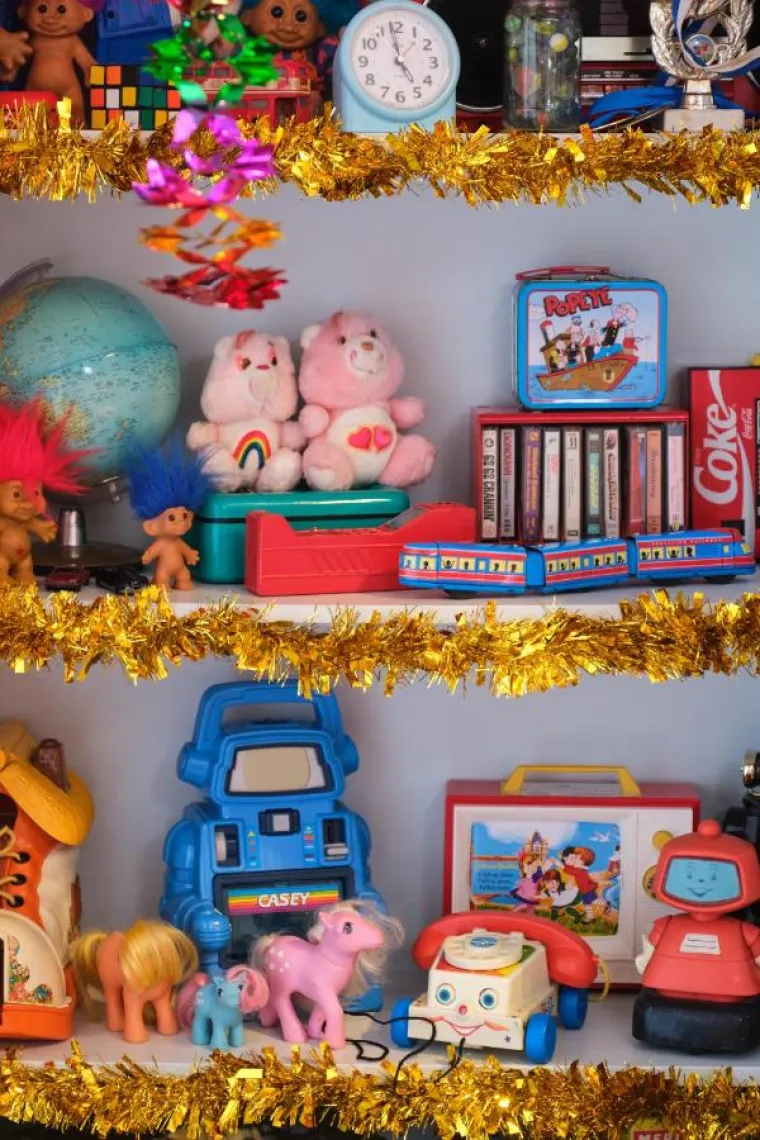 U dječjoj sobi nalaze se klasične igračke poput neodoljivih &quot;Trolls&quot; figura s njihovim šarenim, razbarušenim kosama i omiljenih &quot;Care Bears&quot; lutaka koje svojim toplim osmjesima i prepoznatljivim simbolima na trbuščićima donose čaroliju i radost svakom djetetu. 