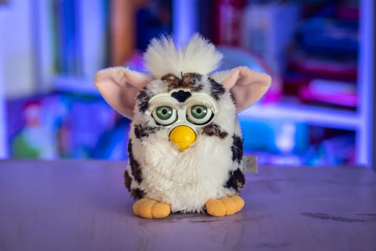 FURBY - Kada se pojavio krajem 90-ih, odmah je postao jedan od najpoželjnijih božićnih poklona tog desetljeća. Ovaj slatki, interaktivni plišanac, koji je izgledao kao mješavina sove i hrčka, bio je više od obične igračke – on je &quot;živio&quot;, pričao i reagirao na dodir, što ga je činilo apsolutnim hitom ispod božićnog bora.