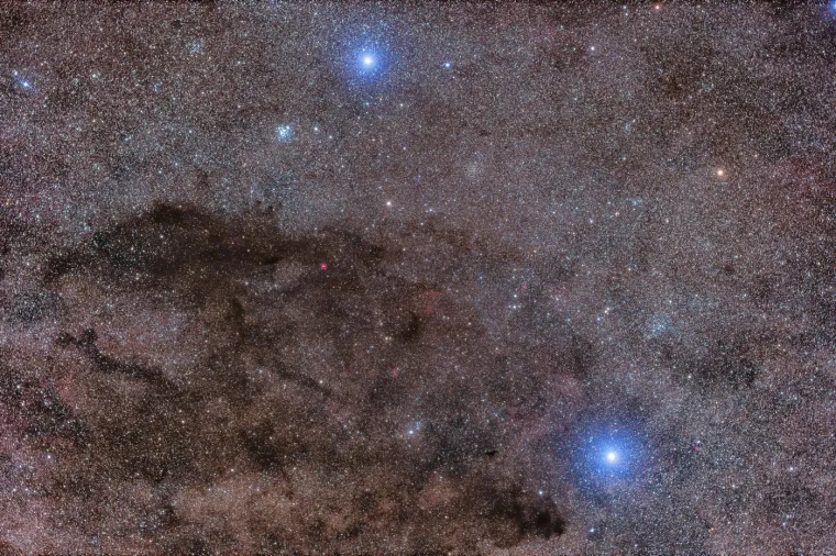 Vreća ugljena (tamna maglica) u zviježđu Crux, prepoznaje se po kontrastu sa svijetlim zvijezdama Acrux i Becrux. Pored nje, nalaze se zvjezdani skupovi NGC 4755 i Trumpler 20, koji čine bogate detalje. Fotografija snimljena u ožujku 2024. iz Australije, prikazuje fascinantnu igru svjetla i tame na nebu.