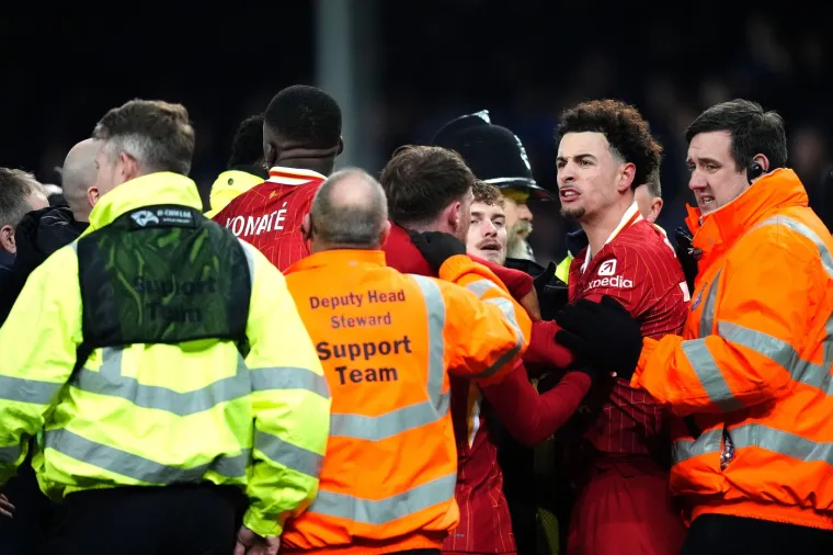 &quot;Sijevalo je sa svih strana tijekom žestoke tučnjave koja je privukla pozornost igrača obje momčadi, policije, redara i šefa Redsa Slota, kojemu je zatim sudac Michael Oliver pokazao crveni karton. Pomoćnik menadžera Redsa Sipke Hulshoff također je isključen nakon žestoke svađe s dužnosnikom oko Evertonovog izjednačujućeg pogotka. Atmosfera na Goodison Parku bila je usijana nakon što je James Tarkowski udario poluvolejem u osmoj minuti sudačke nadoknade. Slavlje domaćih navijača tada je naglo prekinuto jer je situacija s golom bio pod dugotrajnim VAR pregledom&quot;, piše Daily Mail. 