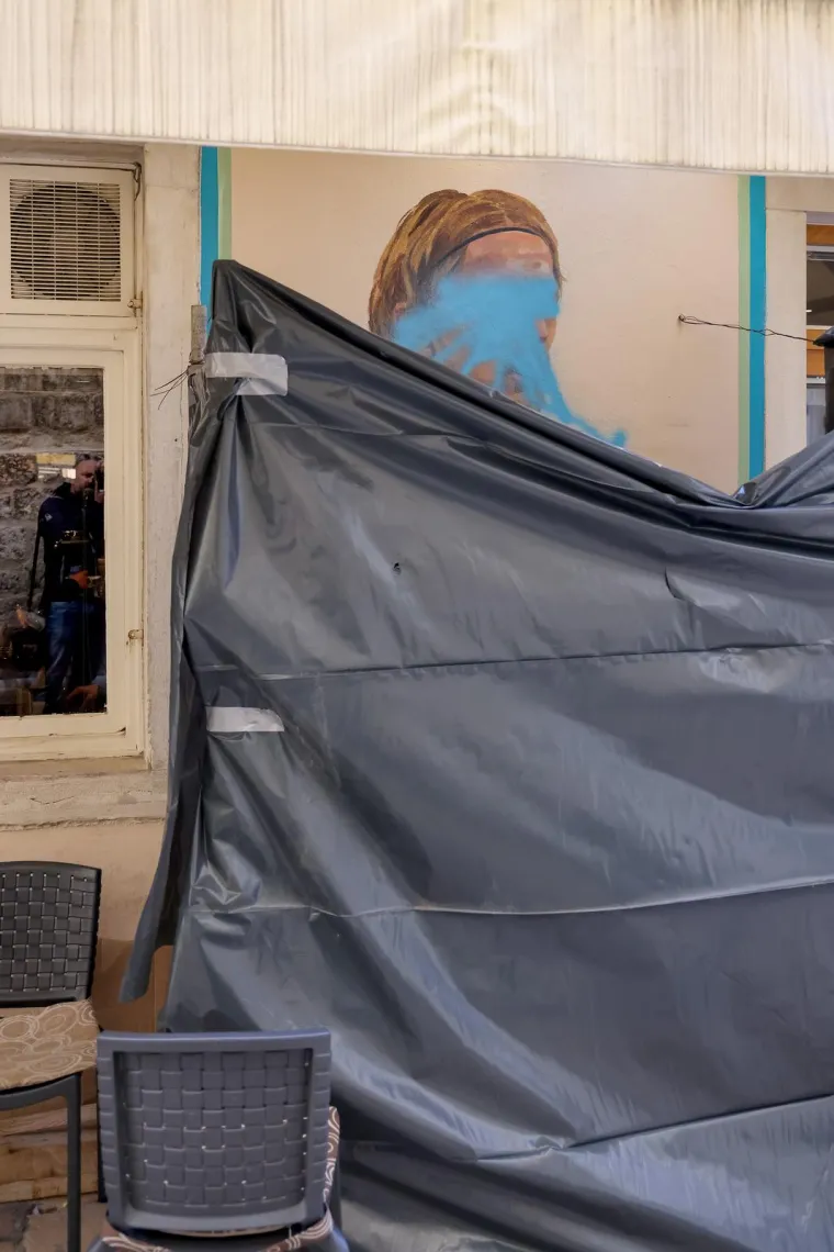 Vlasnici kafića pokušali su prekriti privremeno ovu javnu sramotu, no oskvrnuti mural još uvijek proviruje