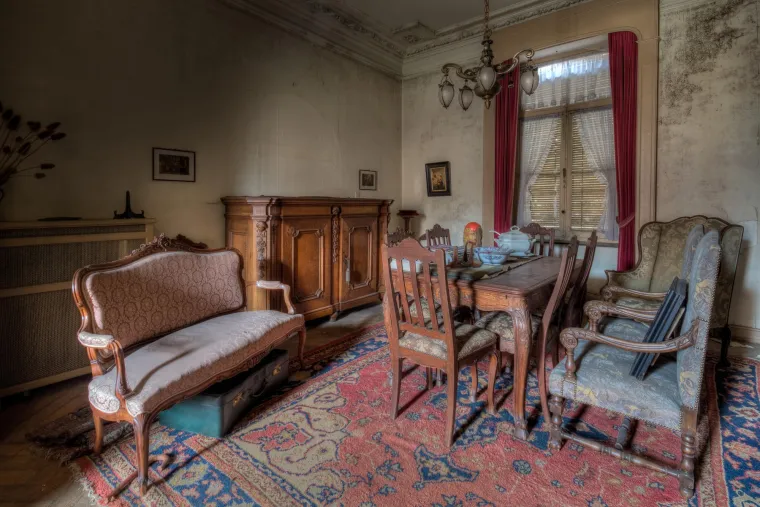MAISON THE BRIDE - Negdje u srcu Belgije, skrivena od znatiželjnih pogleda u malom selu okruženom voćnjacima, stoji vila obavijena velom tajne i tišine – Maison of the Bride, ili &quot;Kuća nevjeste&quot;. Točna povijest vile Maison of the Bride ostaje djelomično nepoznata, što samo doprinosi njenoj mističnoj privlačnosti. Smještena je unutar velikog poljoprivrednog imanja, a prisutnost sanduka s voćem u štalama sugerira da su njeni posljednji stanovnici vjerojatno bili voćari, čiji je život bio vezan uz bogate voćnjake regije. Svoje intrigantno ime, &quot;Kuća nevjeste&quot;, duguje legendi ili sjećanju na vjenčanicu koja je nekoć visjela u ormaru na hodniku gornjeg kata. Taj je detalj postao središnji dio priče o vili, simbol neispunjenih snova ili možda tragične sudbine. Tragovi pronađeni unutar vile, poput gramofona i starih singlica u dnevnom boravku, navode neke istraživače na zaključak da je kuća napuštena negdje oko 1978. godine, no to ostaje nepotvrđena pretpostavka. Posjet vili Maison of the Bride nije jednostavan pothvat. Iako se nalazi uz javnu cestu, oprez je nužan. Susjedi budno paze na imanje i ne ustručavaju se pozvati policiju ako primijete nepoznate osobe. 