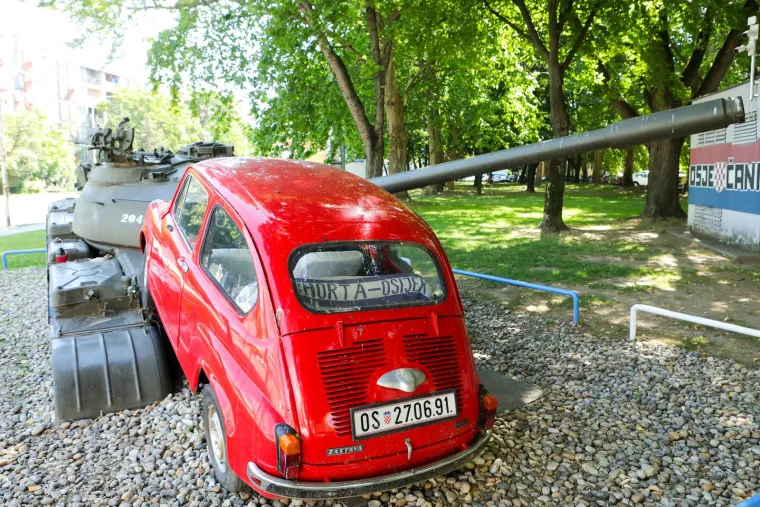 U tom kaosu, na uglu Vukovarske i ondašnje Klajnove ulice, crveni fićo u brzini skreće, naglo koči i staje na križanje kojem se brzo približavaju tenkovi u koloni gazeći sve pred sobom. Tren kasnije iz fiće izlazi Branko Breškić, mlad i visok, kuštravi brko u kratkim bijelim hlačama, tren zastaje, pa se polako odmakne. Par sekundi kasnije tenk se u punoj brzini zabija u sitnog fiću, gura ga pred sobom i nakon desetak metara smrskava ga i drobi.