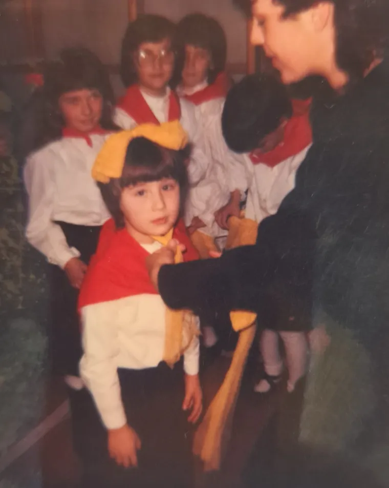 &quot;Bila sam među najmanjima u svojoj generaciji. Sjećam se da su susjedi i rodbina stalno komentirali kako je torba veća od mene, što naravno nije bila. Mnogi su mojim roditeljima znali reći, kako vam je nije žao dati ju u školu tako rano. Imala sam šest godina i znala sam sva slova, a početak škole sam jedva dočekala. Nije mi bilo važno ni kolika mi je torba, ni kolika sam ja, veselila sam se drugim džacima i svom mjestu u učionici. Ponekad bi me tata vozio na biciklu ili bi s njim došao po mene, jer ruku na srce, ona torba je stvarno izgleda disproporcionalno velika i teška na mojim leđima, kao da će me slomiti. Crveno plava sa žutim rubom, u ono vrijeme mnogi su imali takvu. Svake sljedeće godine, na prvi dan škole najvažnije je bilo vidjeti sve one koji su nam tijekom ljeta nedostajali, simpatije, prijatelji. Nije tada bilo društvenih mreža, pa čak niti telefona s kojima bismo tijekom praznika mogli ostati u kontaktu. Himna se nije izvodila na početku nastave, ali se izvodila na svim školskim i drugim priredbama, štoviše, izvodile su se obje, redom, prvo Hej Slaveni, zatim Lijepa naša domovino. Od stjecanja samostalnosti i neovisnosti, samo Lijepa naša domovino. Pjevala sam u folklornim skupinama, u zboru muzičke škole i u crkvenim zborovima, od prvog razreda do kraja fakulteta. Znalo se kad i gdje je himni mjesto. Među rijetkim fotografijama koje imam kao školarac su one sa primanja u pionire, mislim da smo bili pretposljednja generacija. Kada smo trebali stati na pozornicu i izvesti pred svima našu točku, nas nekoliko, umjesto kapa imali smo žute mašne. Netko je prokomentirao „niste ono što vam vlast stavlja na glavu, nego ono što vam je u glavi, potrudite se da u sebi nosite znanje i dobrotu“. Manje-više, to je ono što i ja želim poručiti svim današnjim školarcima.&quot;