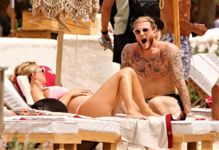 Atraktivna voditeljica privlači poglede i upija zrake sunca na plaži, a njezin dragi uz nju zijeva