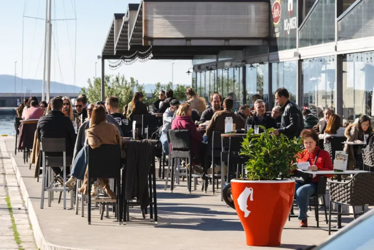 Dok zanosna plavu&scaron;a ispija kavu, djevojke u bikinijima hvataju prve zrake sunca
