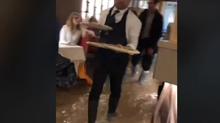 U poplavljenom restoranu konobari u čizmama raznose pizze nasmijanim gostima