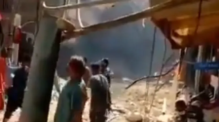 Iznad zgrada uzdiže se gusti crni dim, ljudi na ulicama