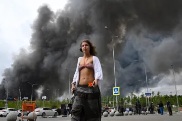 Rat? To nije njena briga! Polugola, sa slu&scaron;alicama na u&scaron;ima dok iza nje - Moskva gori